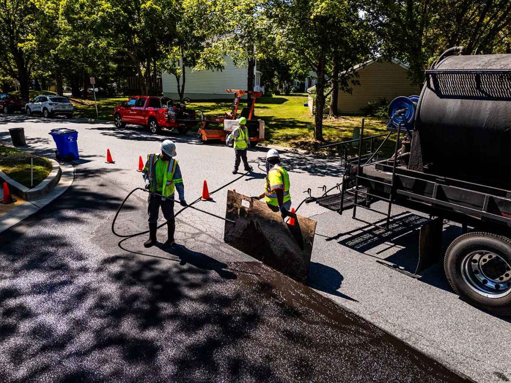 Contractors performing sealcoating at a job site