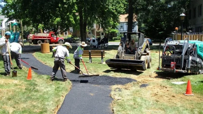 Contractors using a rake to lay fresh asphalt