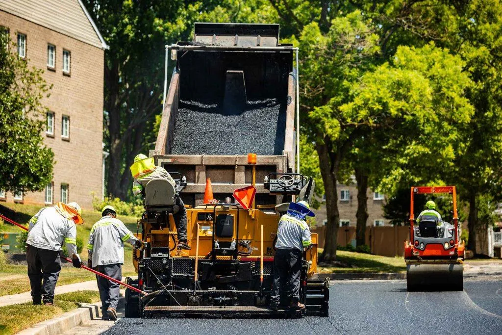 Contractors smoothing a layer of asphalt on a road