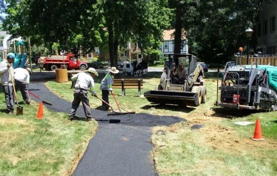 Contractors using a rake to lay fresh asphalt