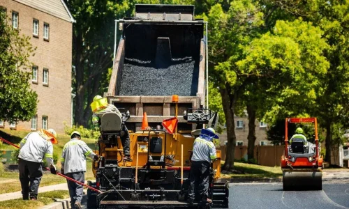 Contractors smoothing a layer of asphalt on a road