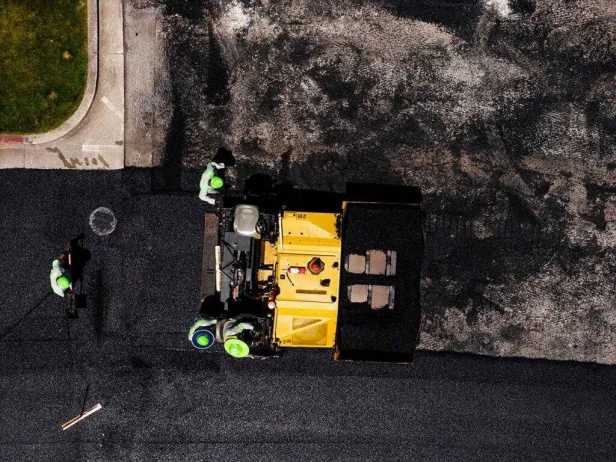 Overhead shot of contractors laying down new and fresh asphalt on road