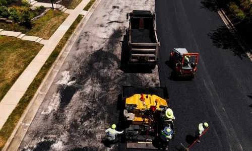 Contractors laying fresh asphalt on a road