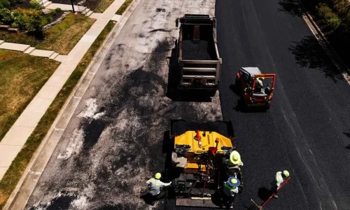 Contractors laying fresh asphalt on a road