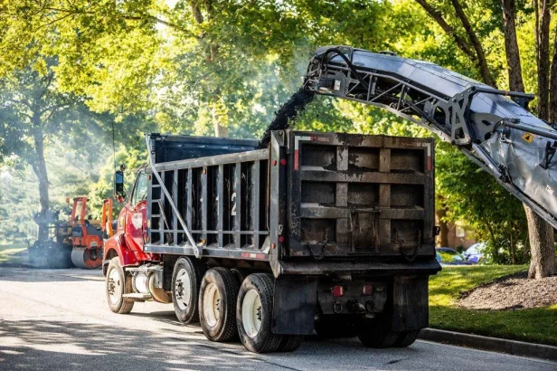 Asphalt Milling Machine Pouring Asphalt Into The Bed of a Work Truck